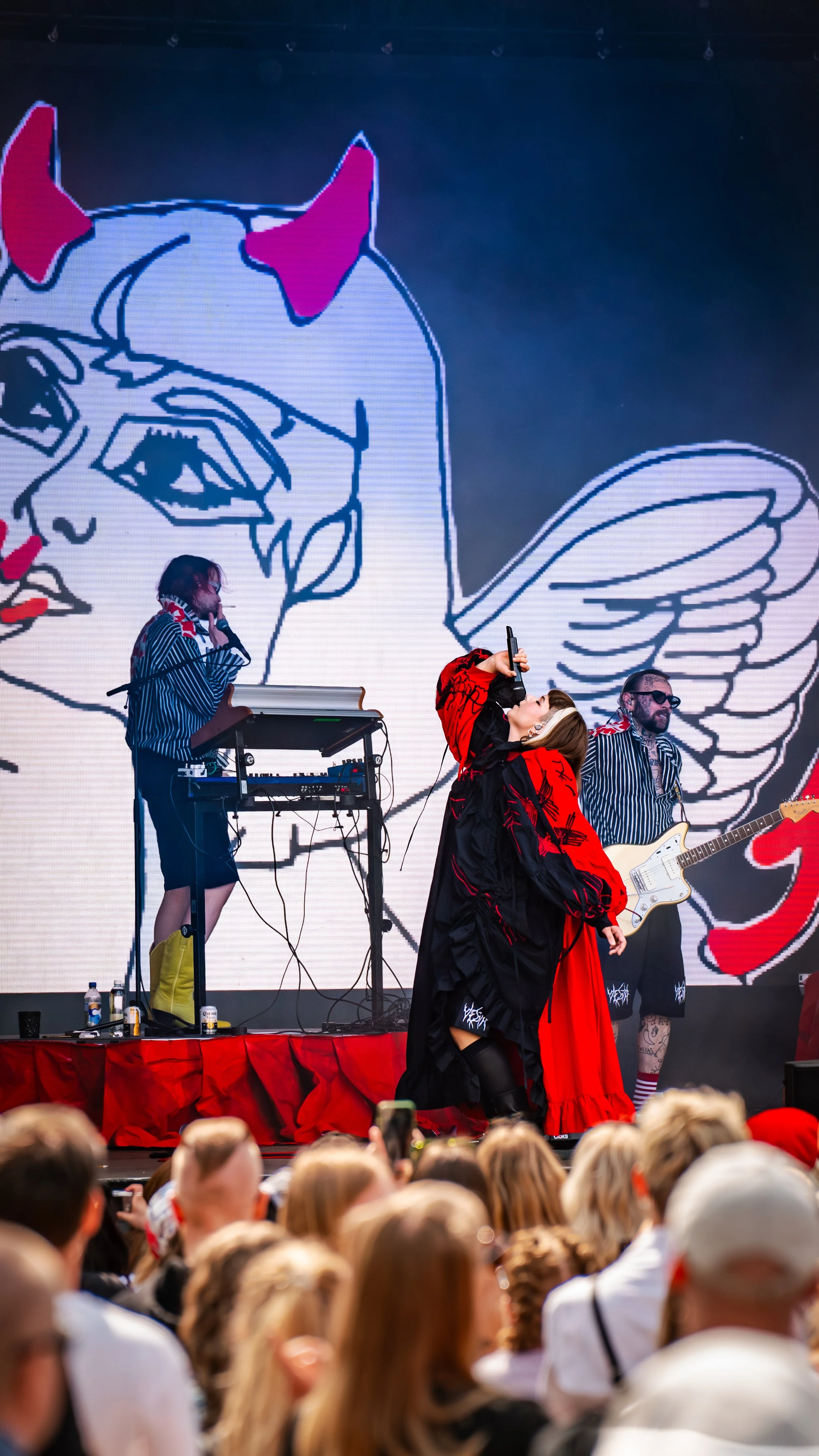 Perhepohjainen musiikkiesitys, jossa kolme esiintyjää lavalla ja suuri digitaalinen taustakuva