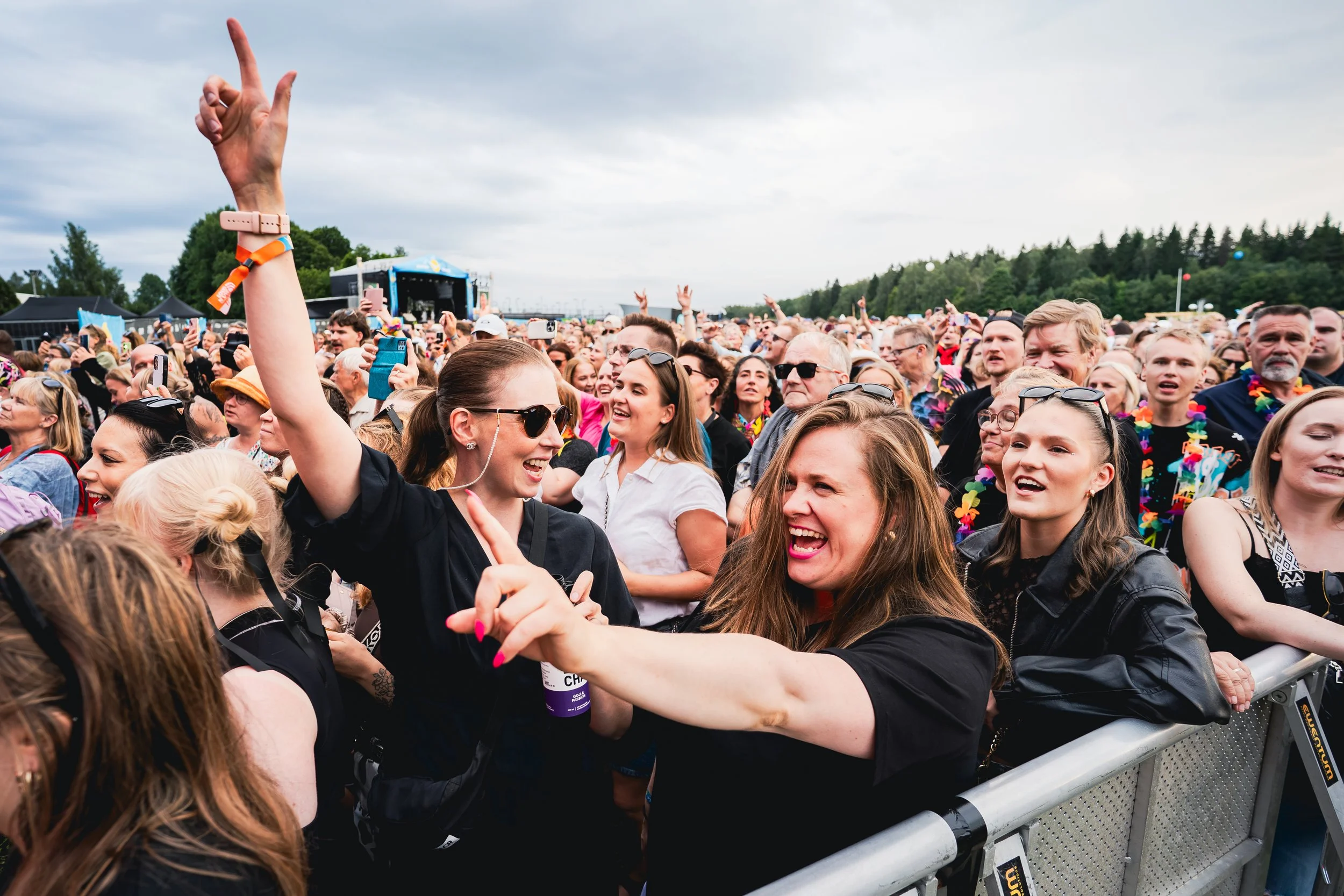 Iloisia ihmisiä konserttiyleisössä nauttimassa musiikista, osa hulivat ja hymyilivät, useat hymyilevät ja juhlivat.