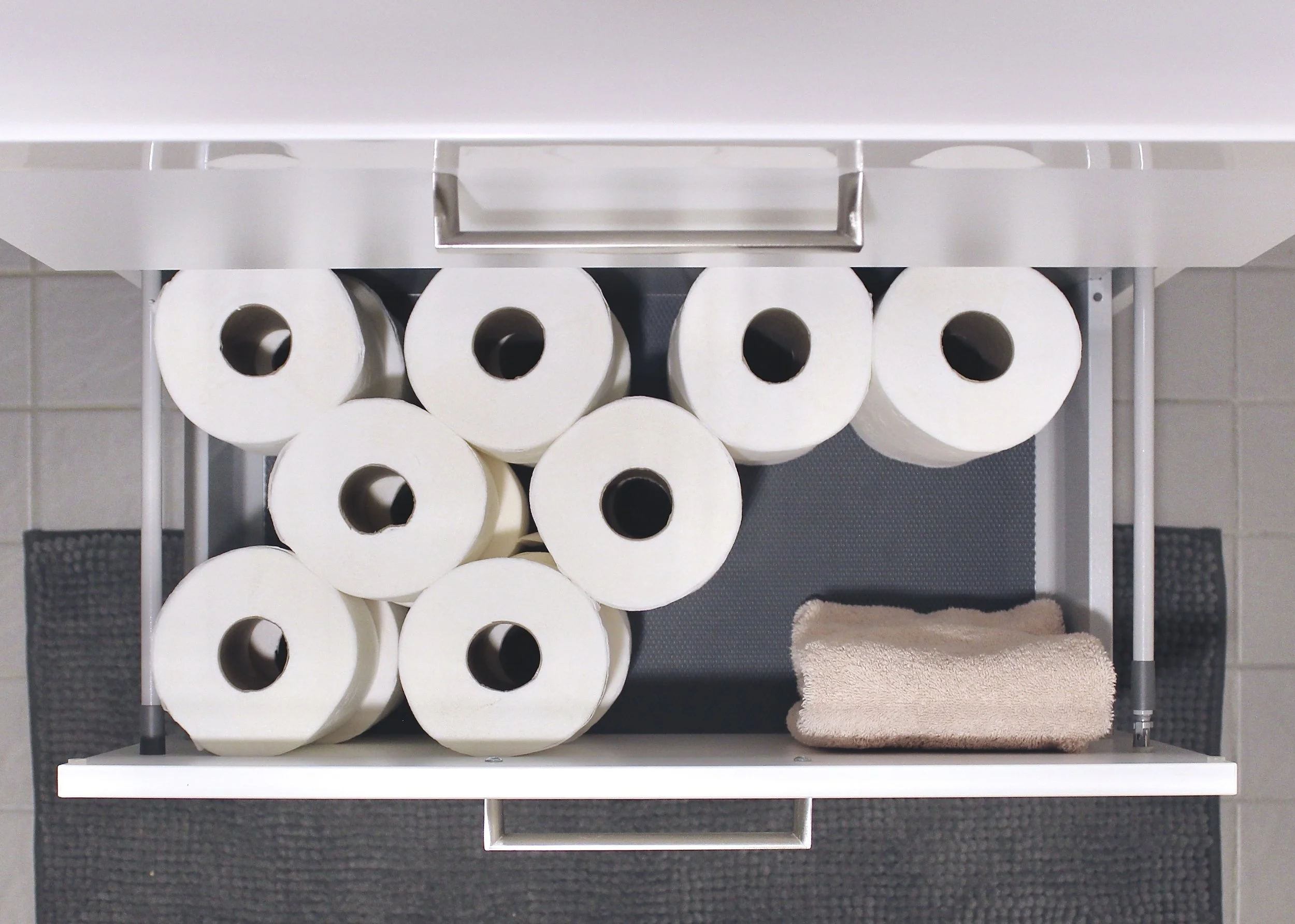 Kuvassa avonainen vetolaatikko, jossa wc-paperirullia ja yksi pyyhe