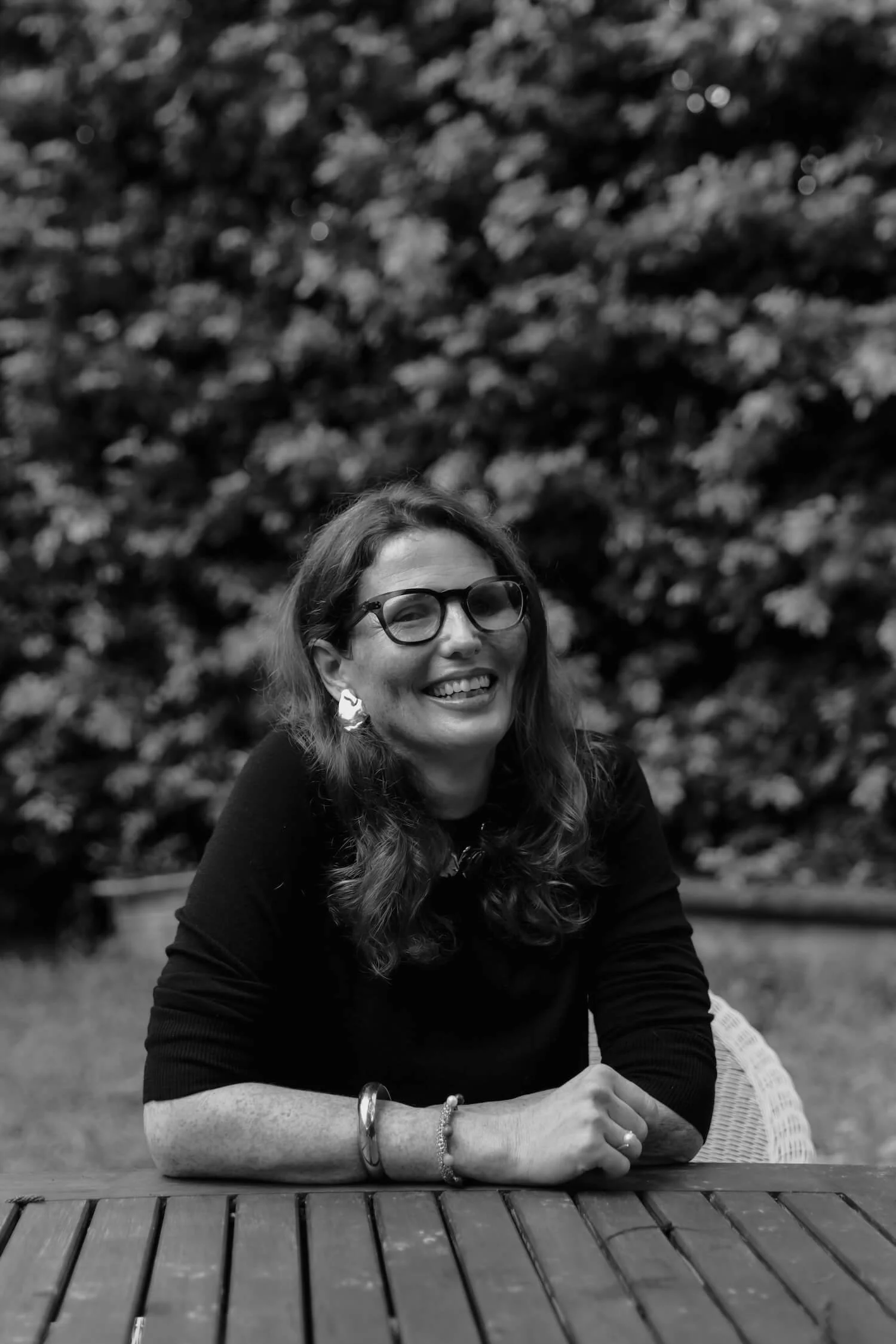 Black-and-white portrait of Phoebe smiling and seated outdoors, reinforcing her warmth and authenticity as an inspirational public speaker in Brisbane.