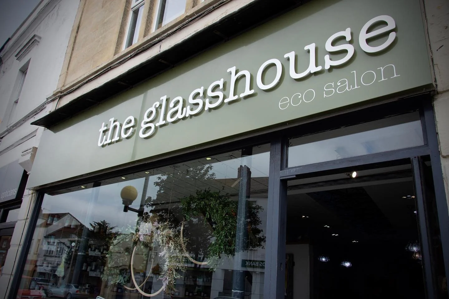 The Glasshouse eco salon storefront with large windows and green signage.