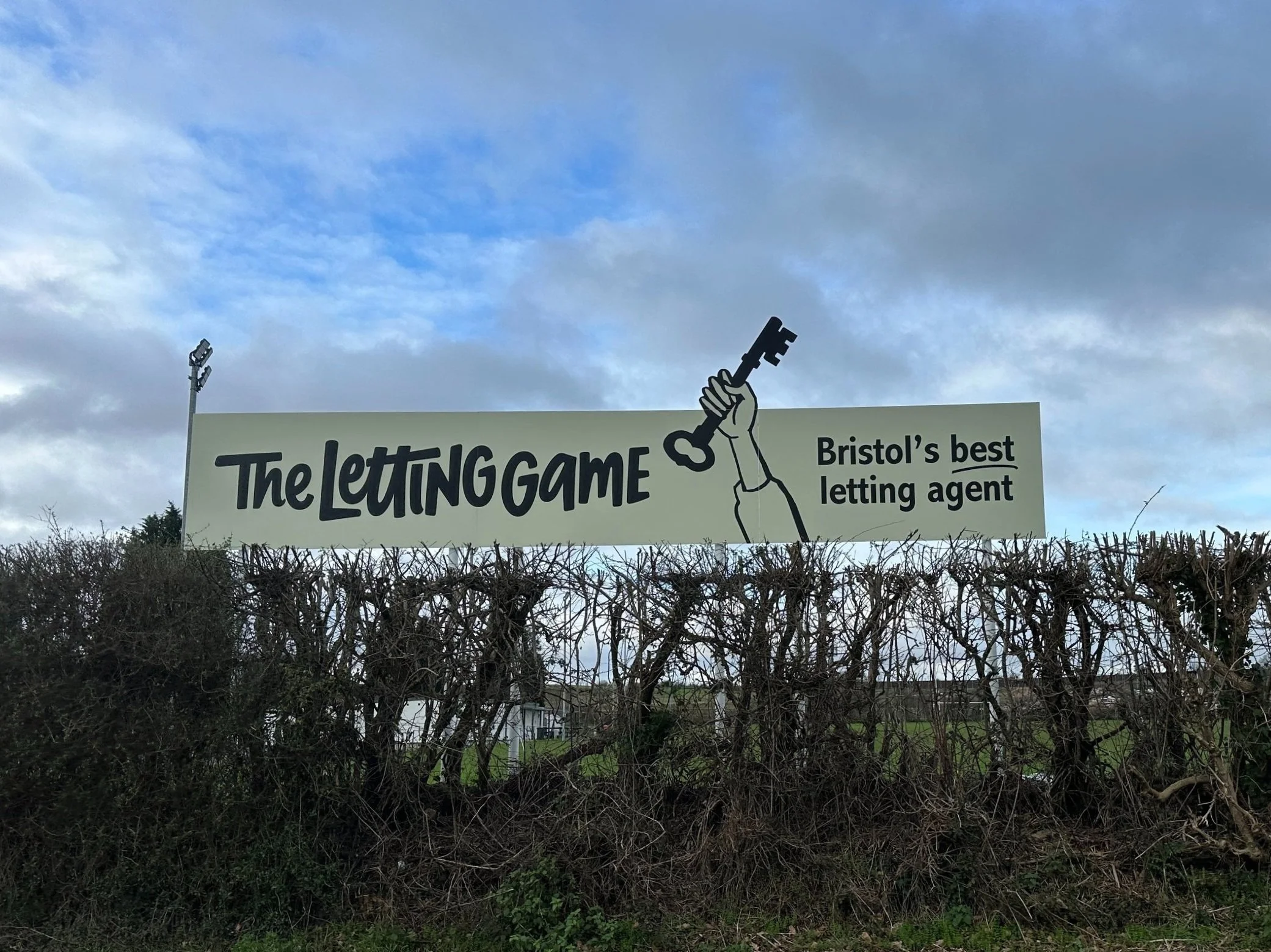Large printed hoarding sign for The Letting Game, Bristol’s best letting agent, with bold typography and illustrated key graphic.