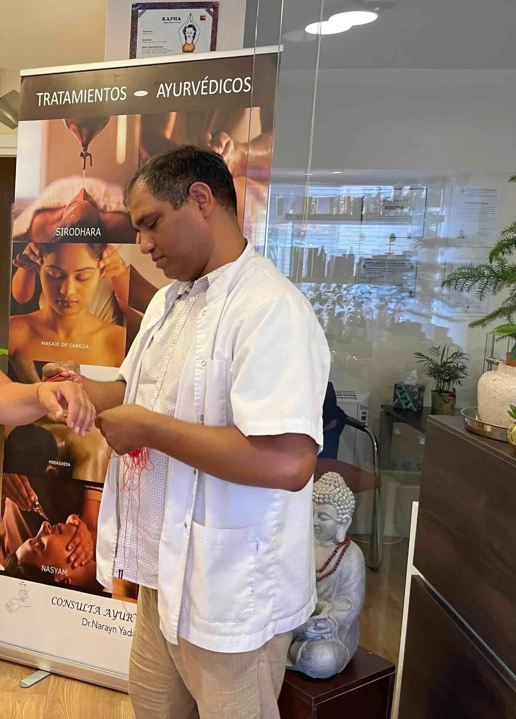 Dr. Narayan Yadav tying a red thread on a person's wrist
