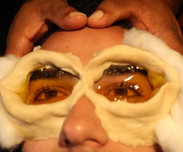 Ayurveda Treatment for Eyes. Person lying with a tank of herbs around of eyes full of oil