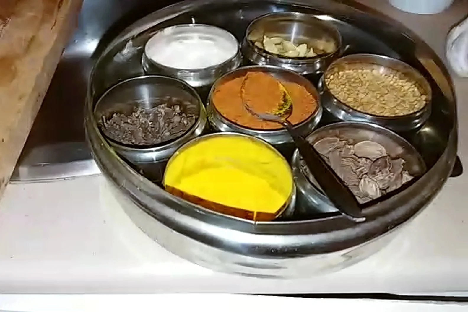 Caja de especias ayurvédica (masala dabba) con cúrcuma, chile, comino, cardamomo y clavo