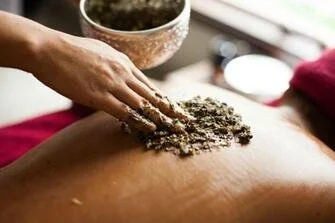 Tratamiento terapéutico ayurvédico Udvartana realizado con polvos herbales, enfocado en procesos de detoxificación y activación metabólica.