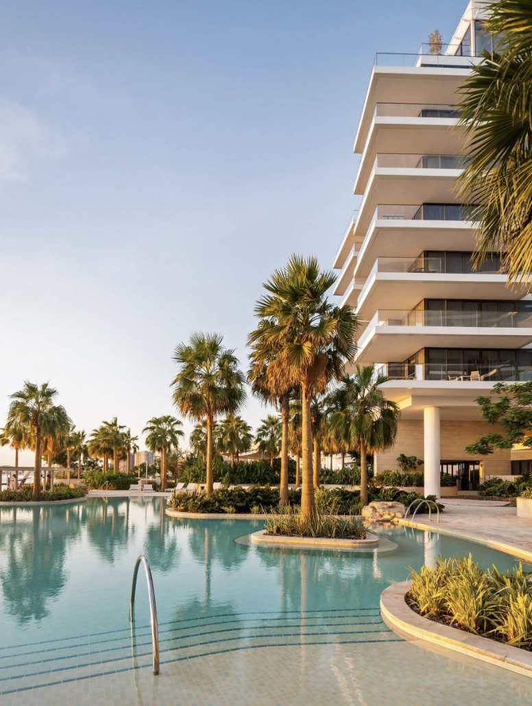 Luxury resort pool with palm trees and modern building at sunset