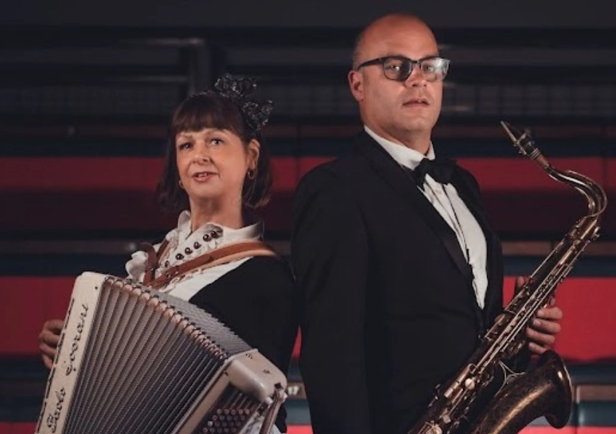 image shows a man and a woman both holding instruments