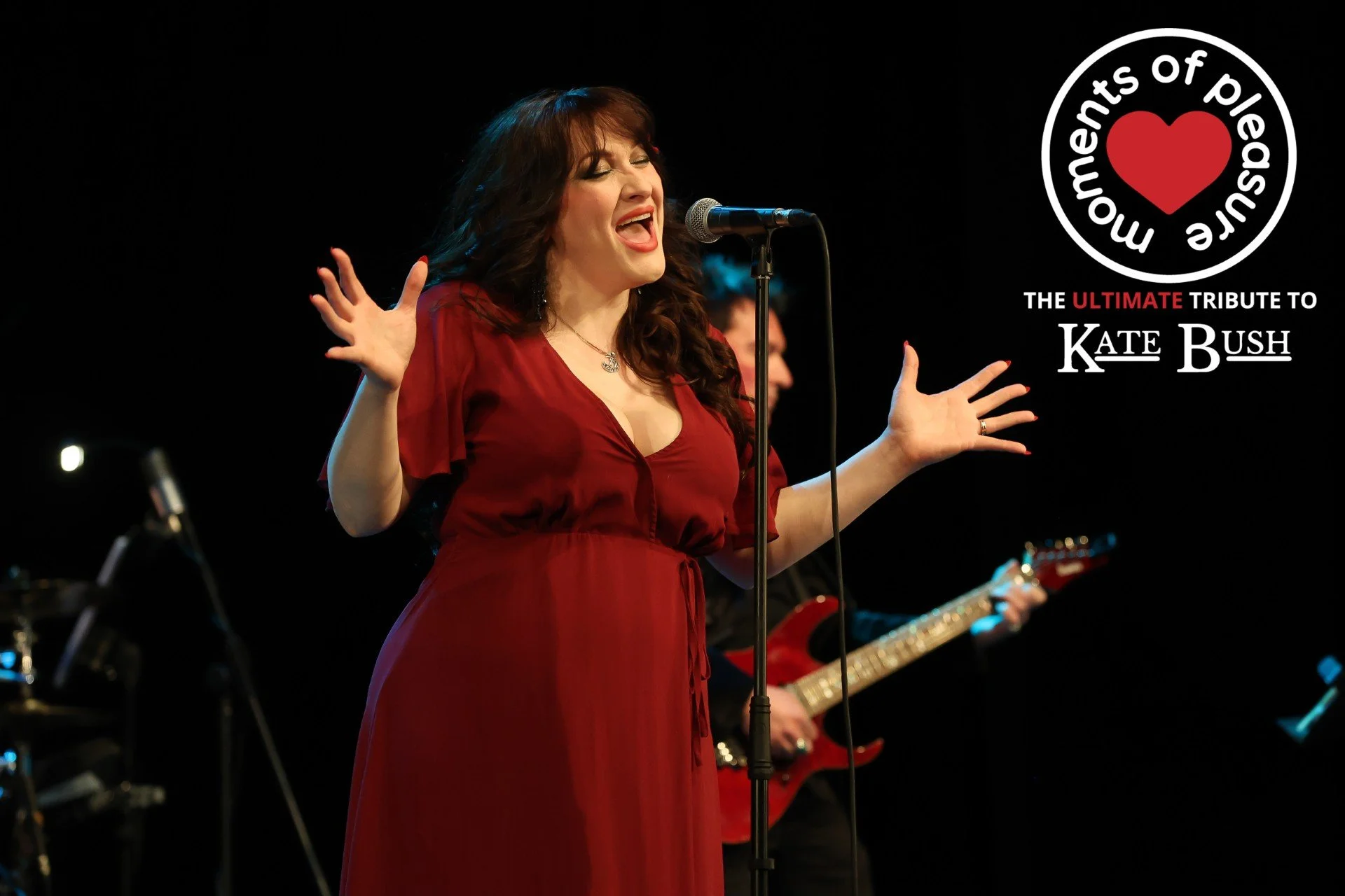 image shows woman in red dress singing into a microphone