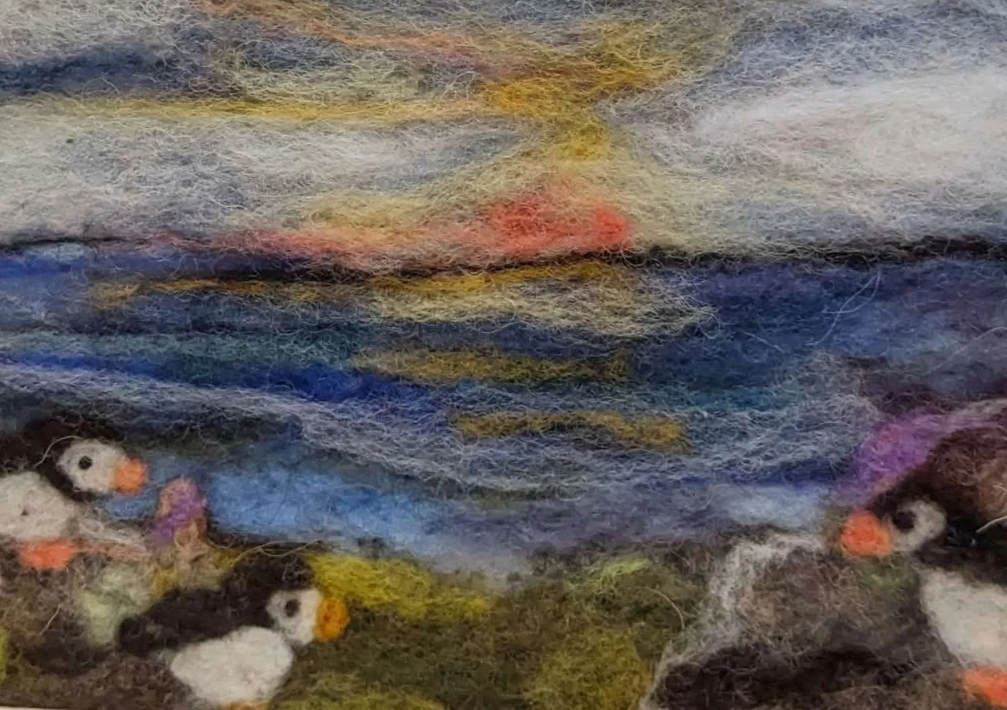 felting artwork showing the ocean a sunset and some penguins
