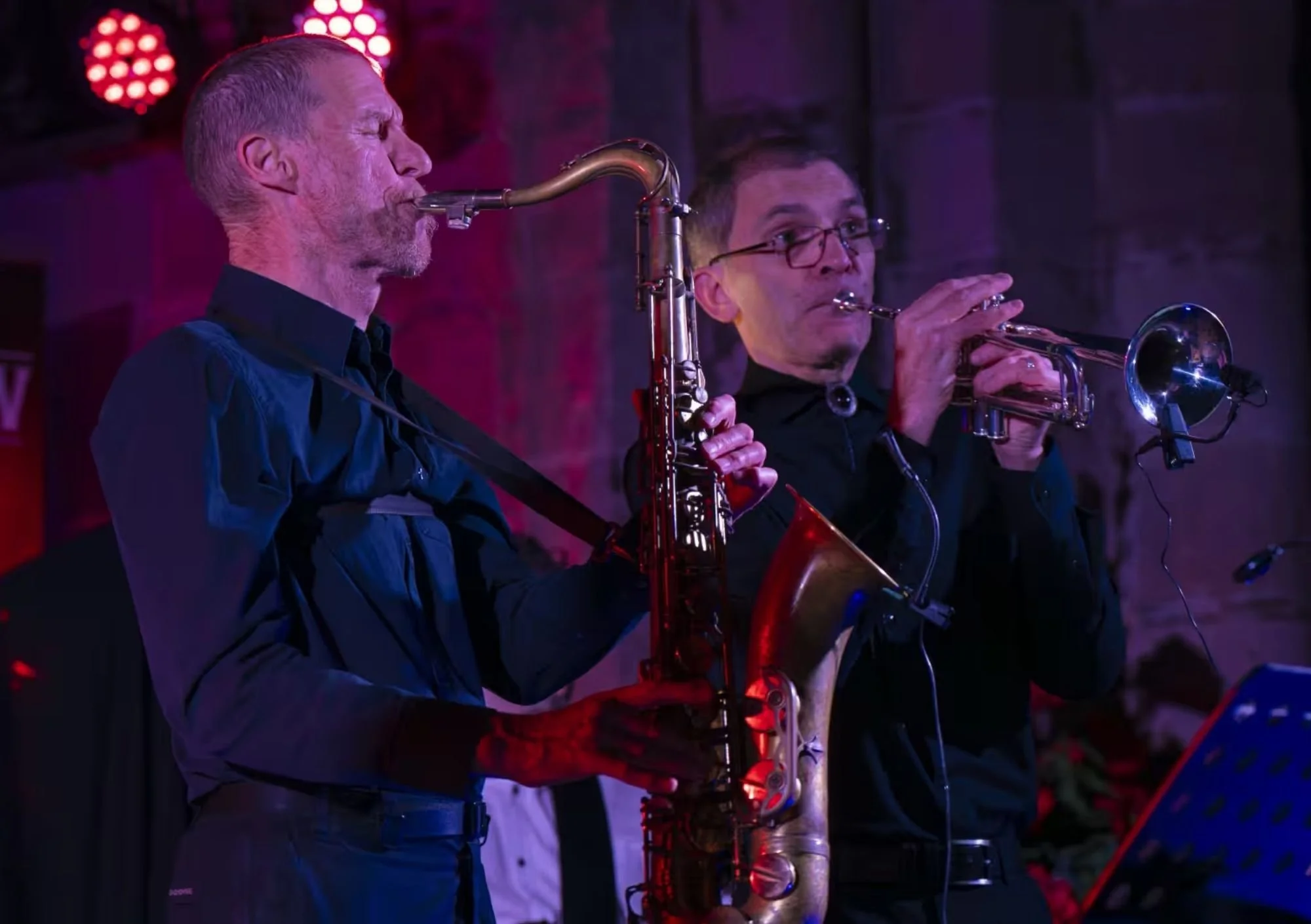 image shows 2 men on stage playing instruments