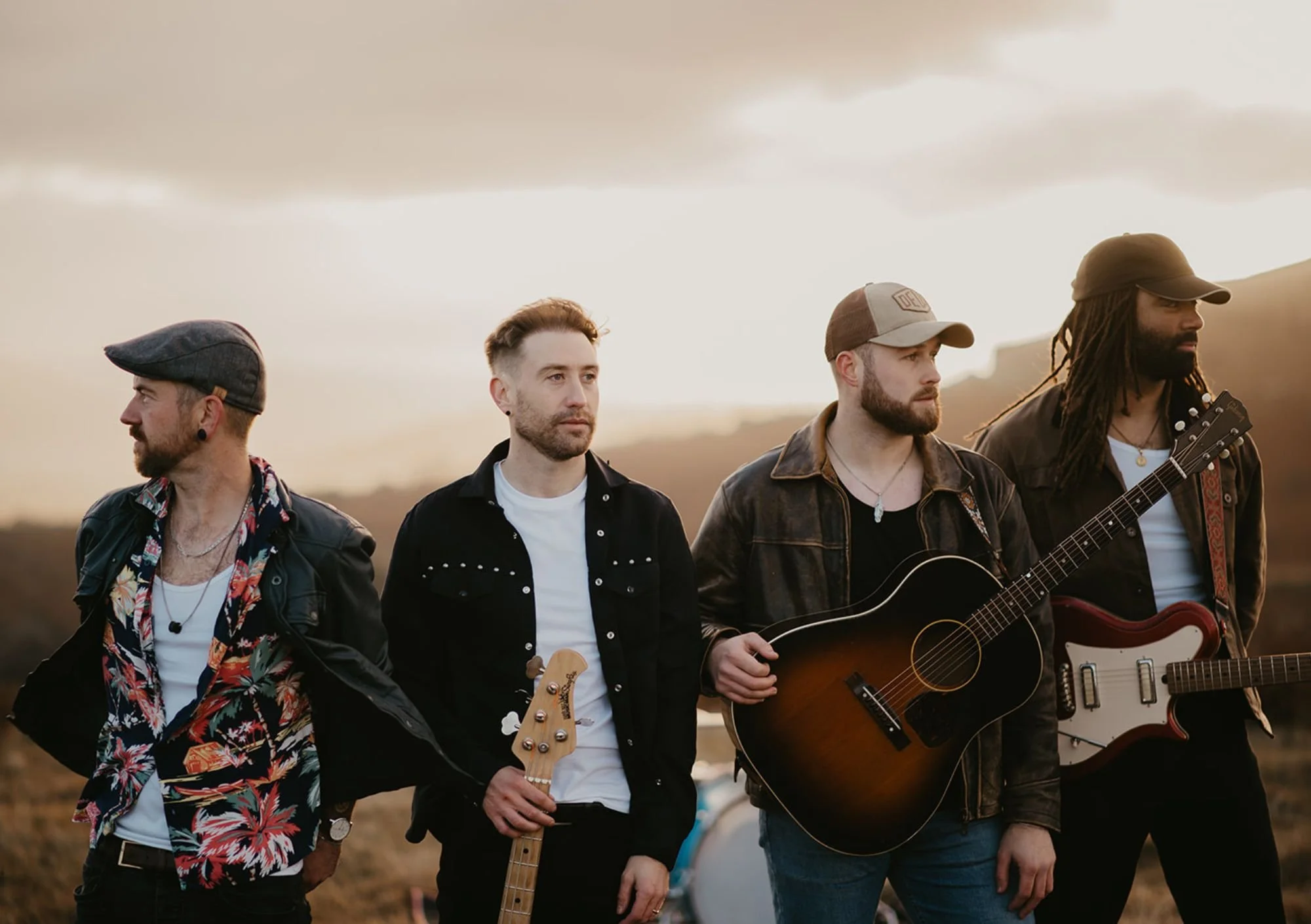 4 men stand outside at dusk holding their instruments