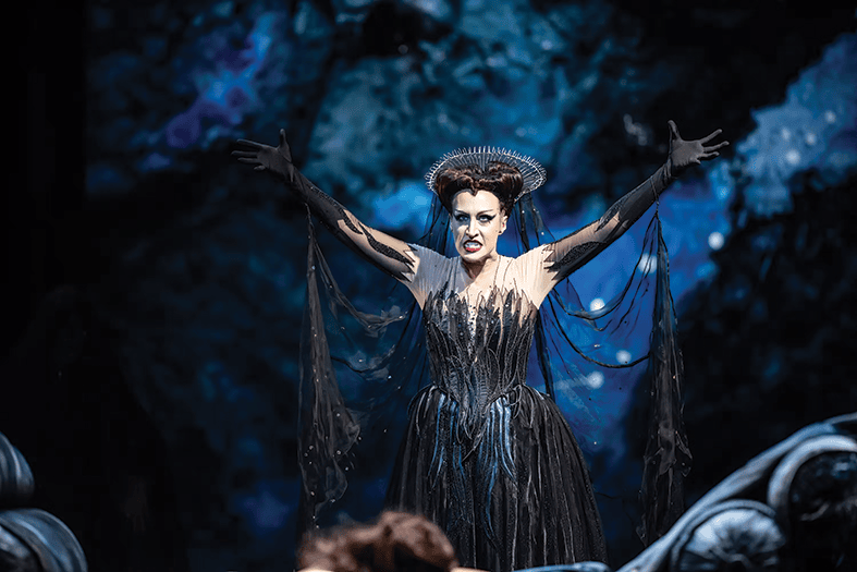 image shows woman wearing black with her arms up