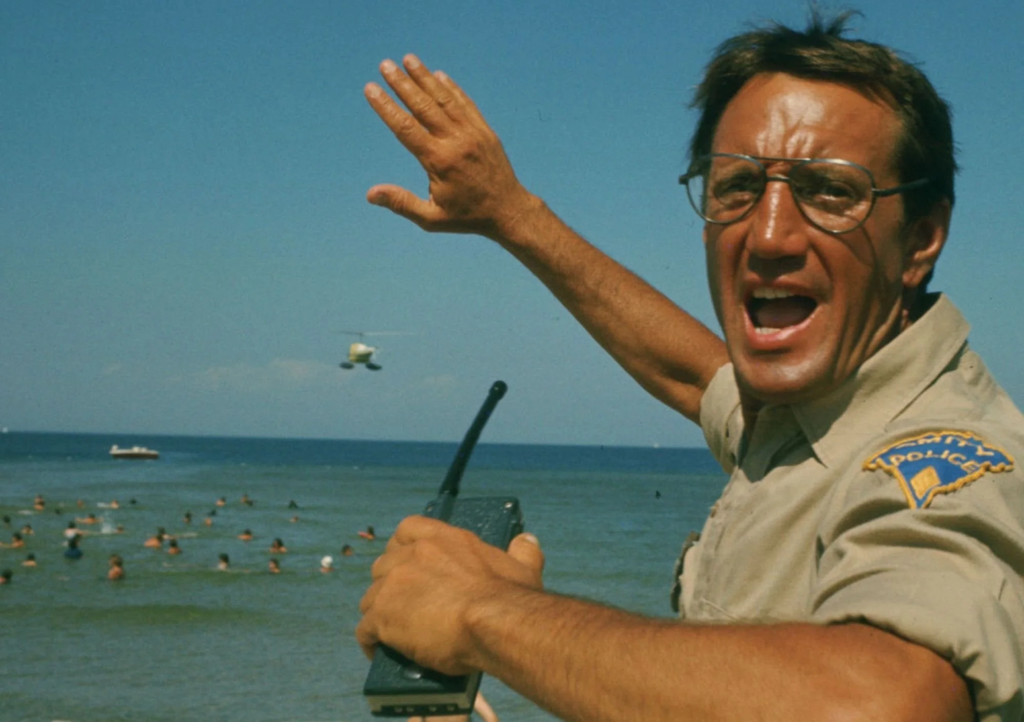 a scene from Jaws, where the sheriff is holding a radio and signalling while near the ocean