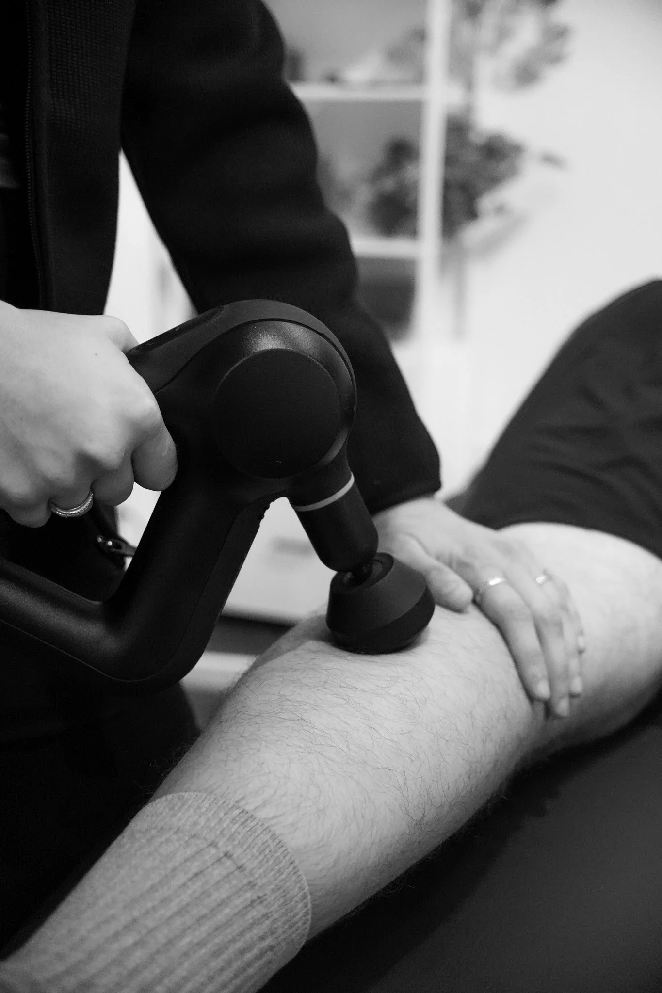 Physical therapist using a handheld therapy device on a patient’s leg