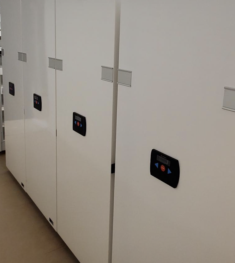 Empty white and blue metal shelving unit in an office or store, with a lockable cabinet door on the right, and a lock on the right-side panel.