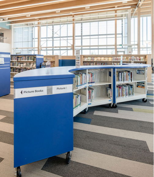 Empty white metal shelving unit with four shelves in a room with white and blue walls and a wood floor.