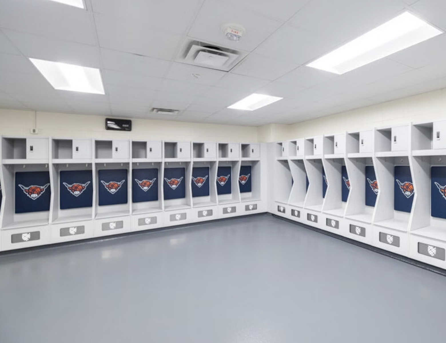 Empty NBA locker room with lockers featuring the New York Knicks logo on blue backgrounds.