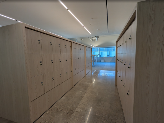 Empty white metal shelving unit with four shelves in a room with white and blue walls and a wood floor.