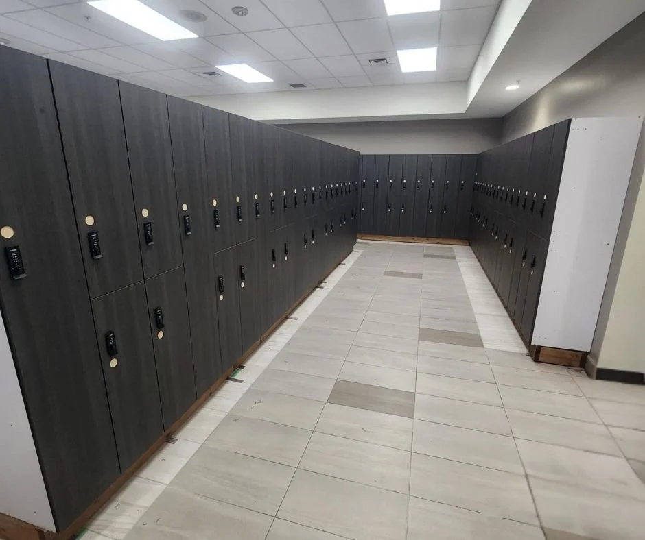 Row of black lockers with digital locks in a school hallway.