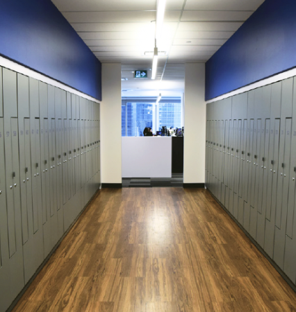 Empty white metal shelving unit with four shelves in a room with white and blue walls and a wood floor.
