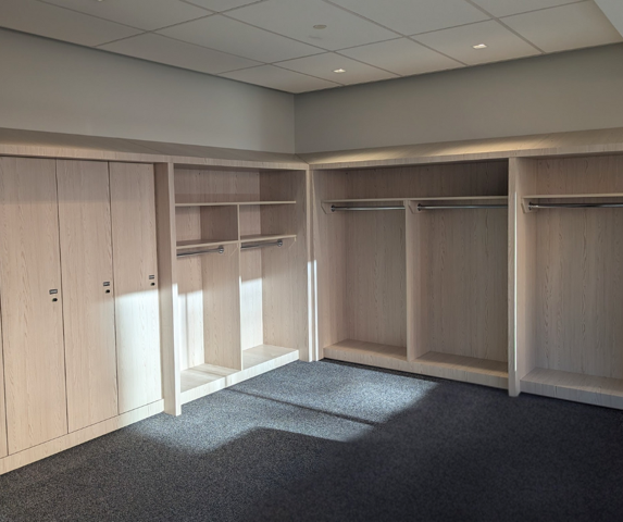 Empty store shelving unit with blue sliding doors, some white shelves, and a black handle, with a small cardboard box on the bottom shelf.