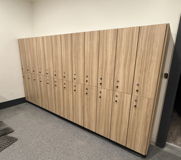Empty white metal shelving unit with four shelves in a room with white and blue walls and a wood floor.