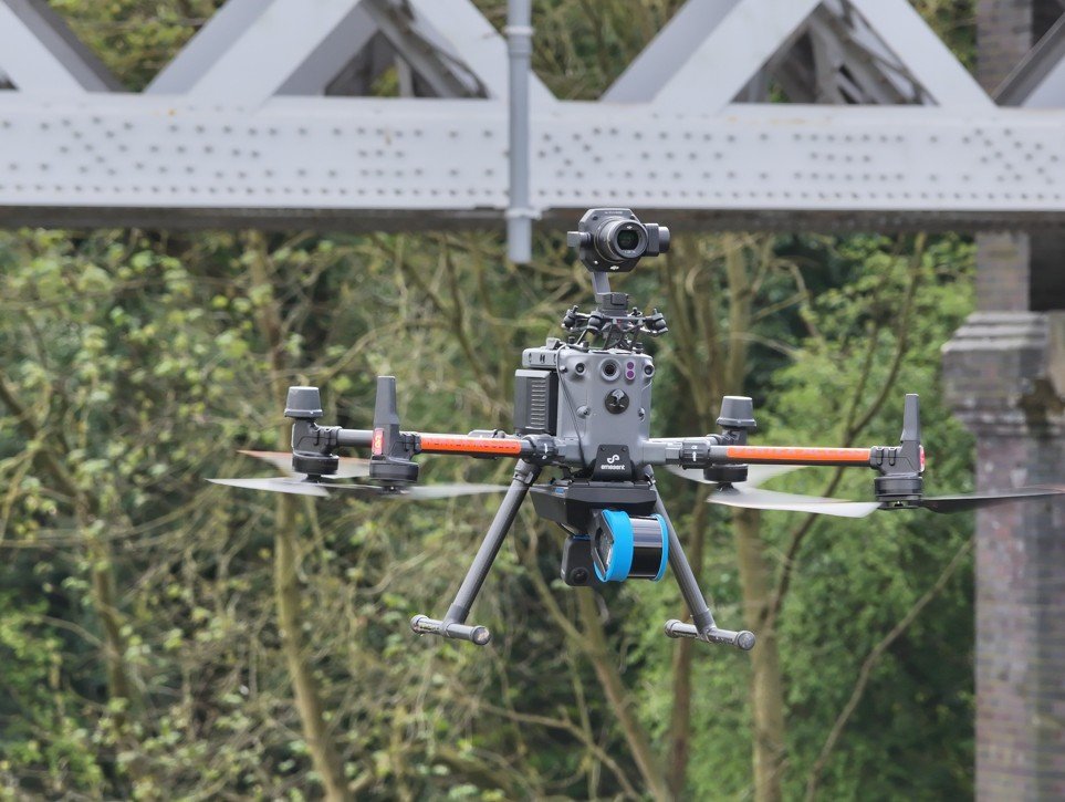 Hovermap ST-X LiDAR scanner flying under a commercial drone for complex mapping.