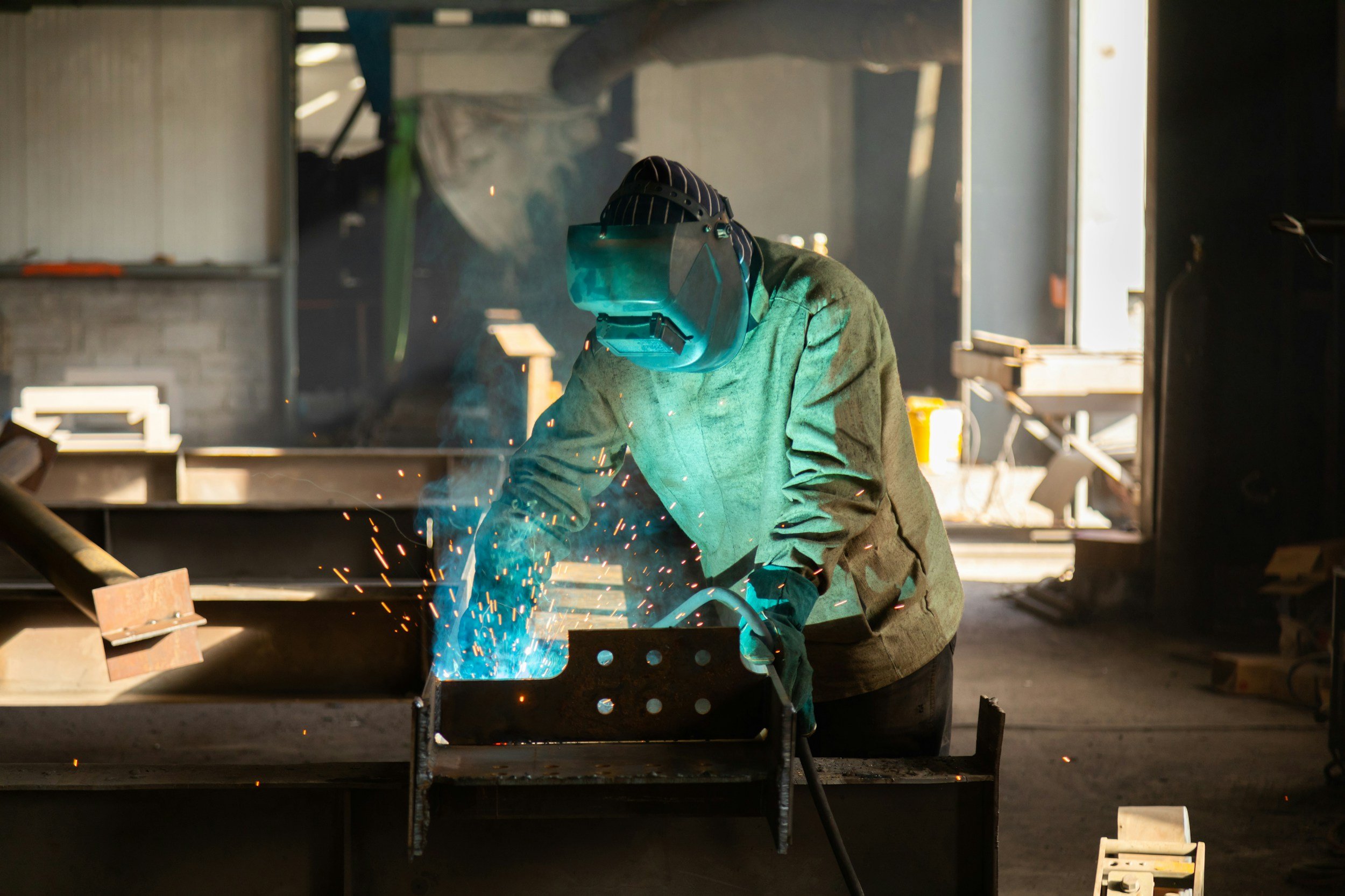 A person welding metal on a workbench in a workshop, with sparks flying.