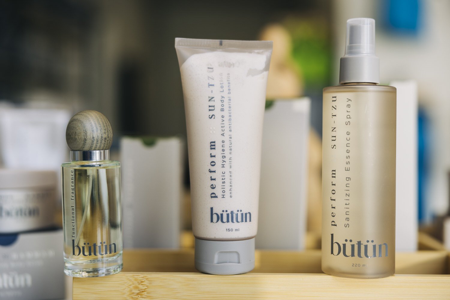 Set of Bütün skincare products, including perfume, exfoliation exfoliant, and antiseptic spray on a wooden tray.