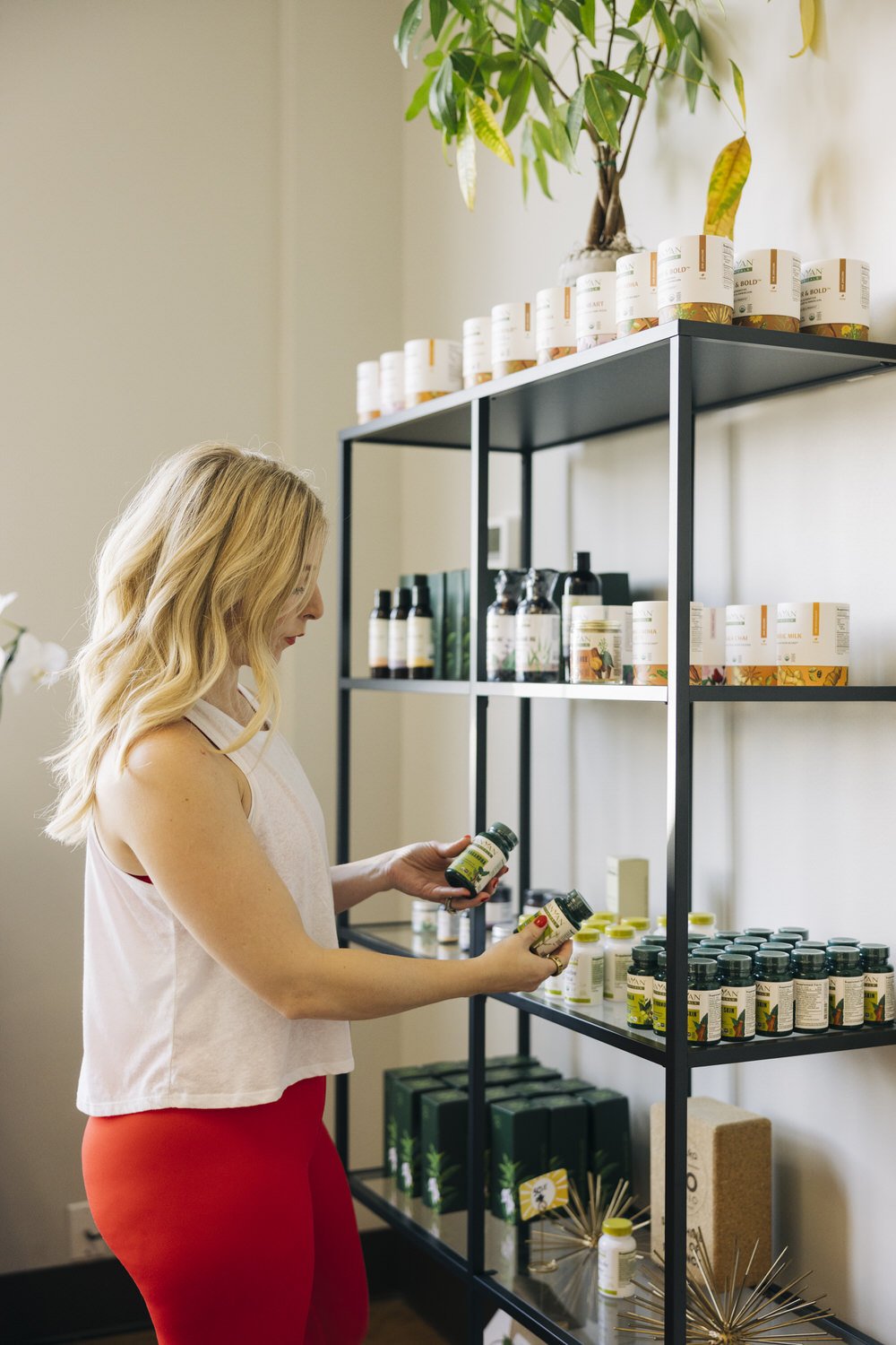 A woman shopping for health supplements or vitamins on black metal shelving units in a store.