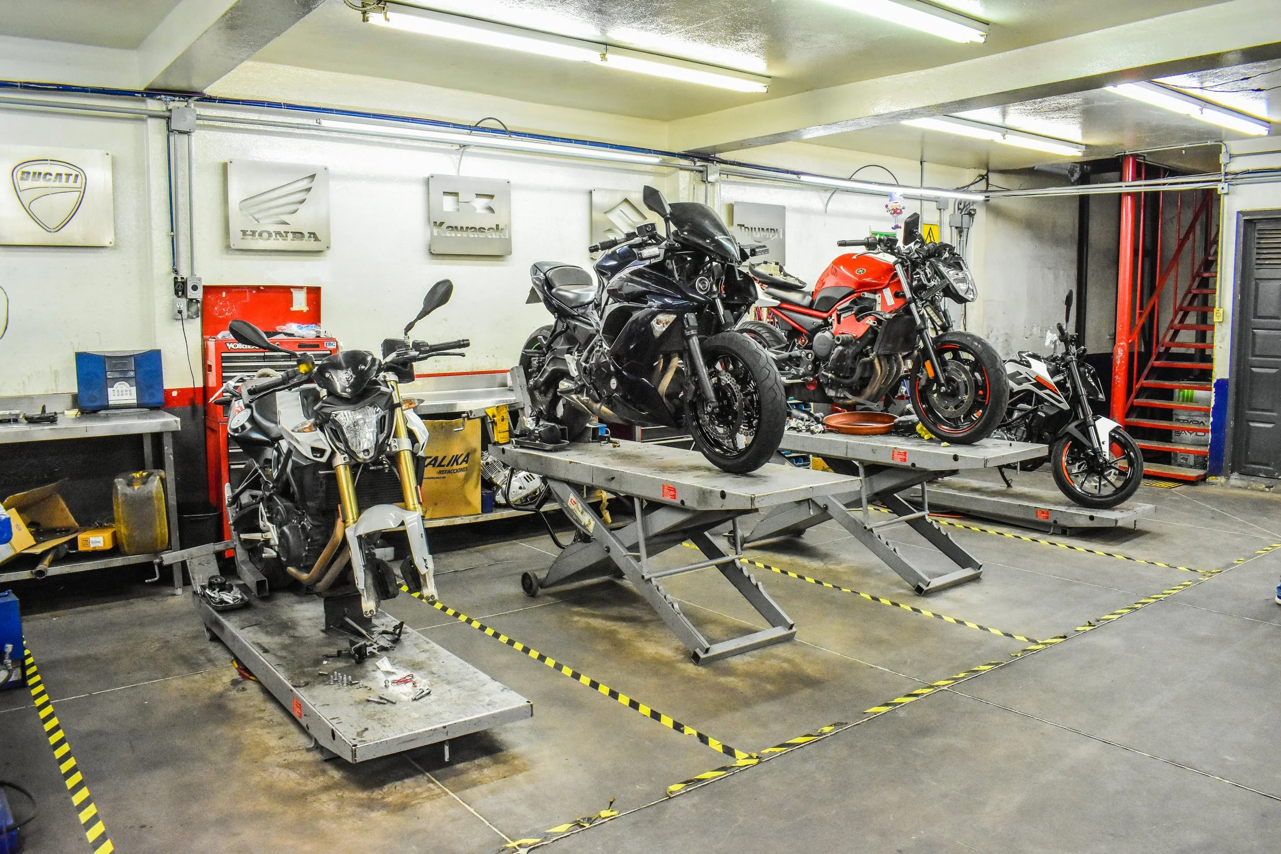 Atelier de réparation de motos avec plusieurs motos sur des tables élévatrices.