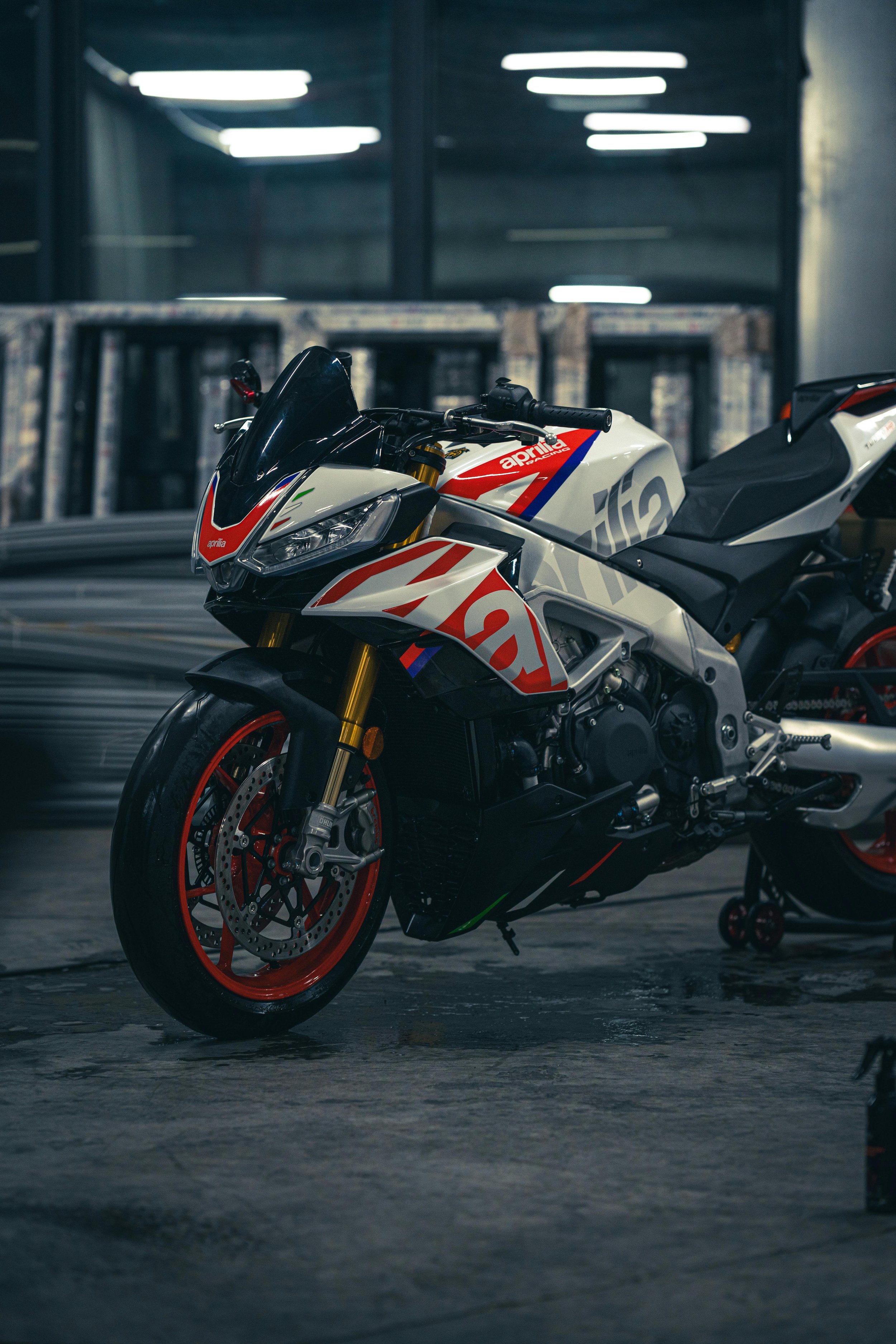 Une moto sportive blanche avec des accents rouges et bleus dans un garage.