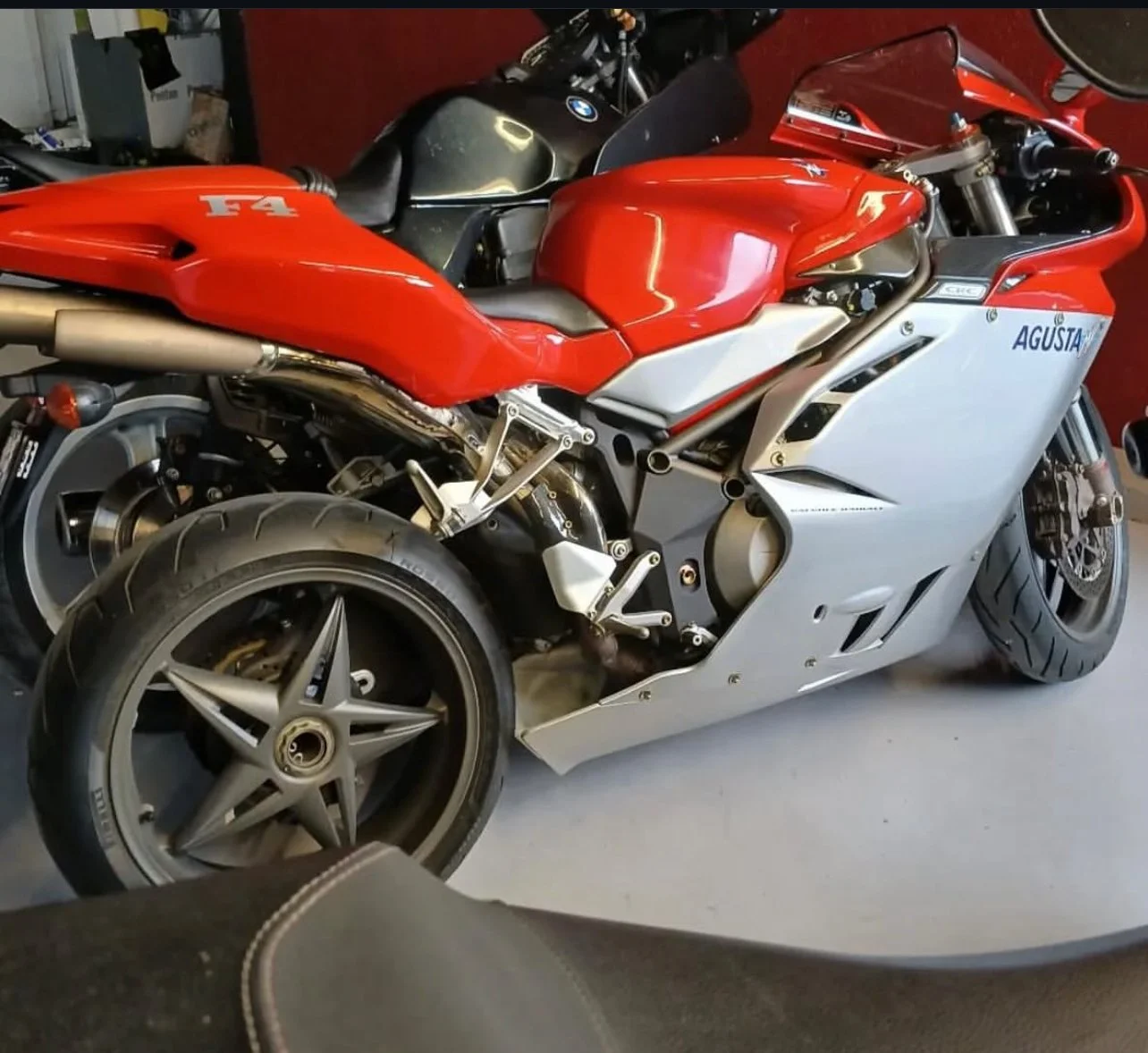 Moto sportive rouge et argent, MV Agusta F4, garée dans un garage.