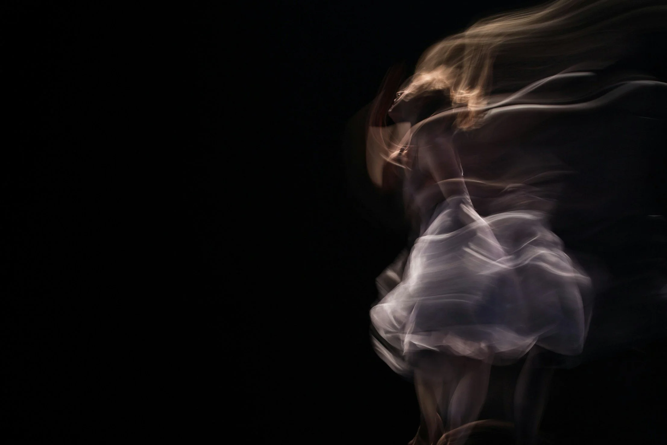 Abstract photo of smoke swirling against a black background.