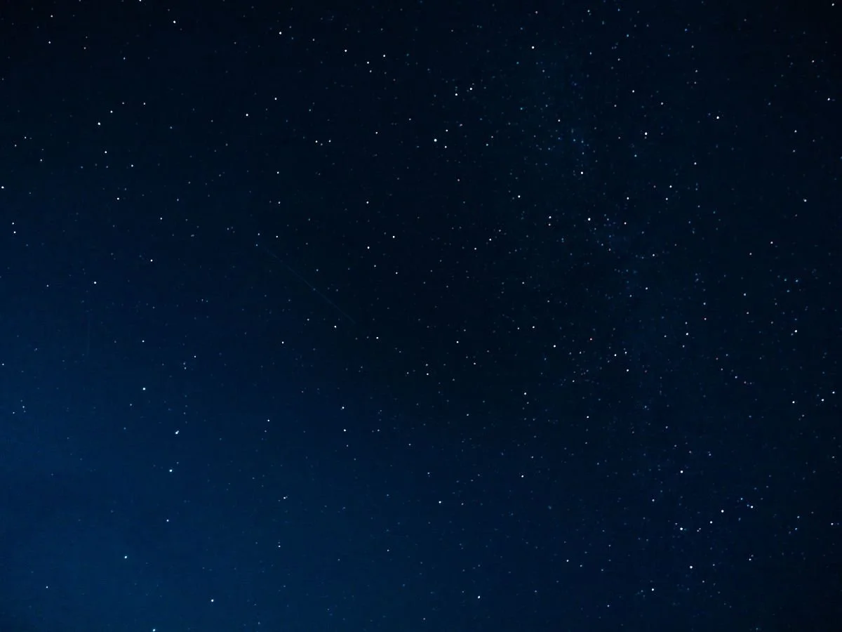 Un cielo notturno limpido, costellato di numerose piccole stelle luminose sparse su uno sfondo blu scuro e profondo. Lo scenario trasmette una distesa tranquilla e infinita.