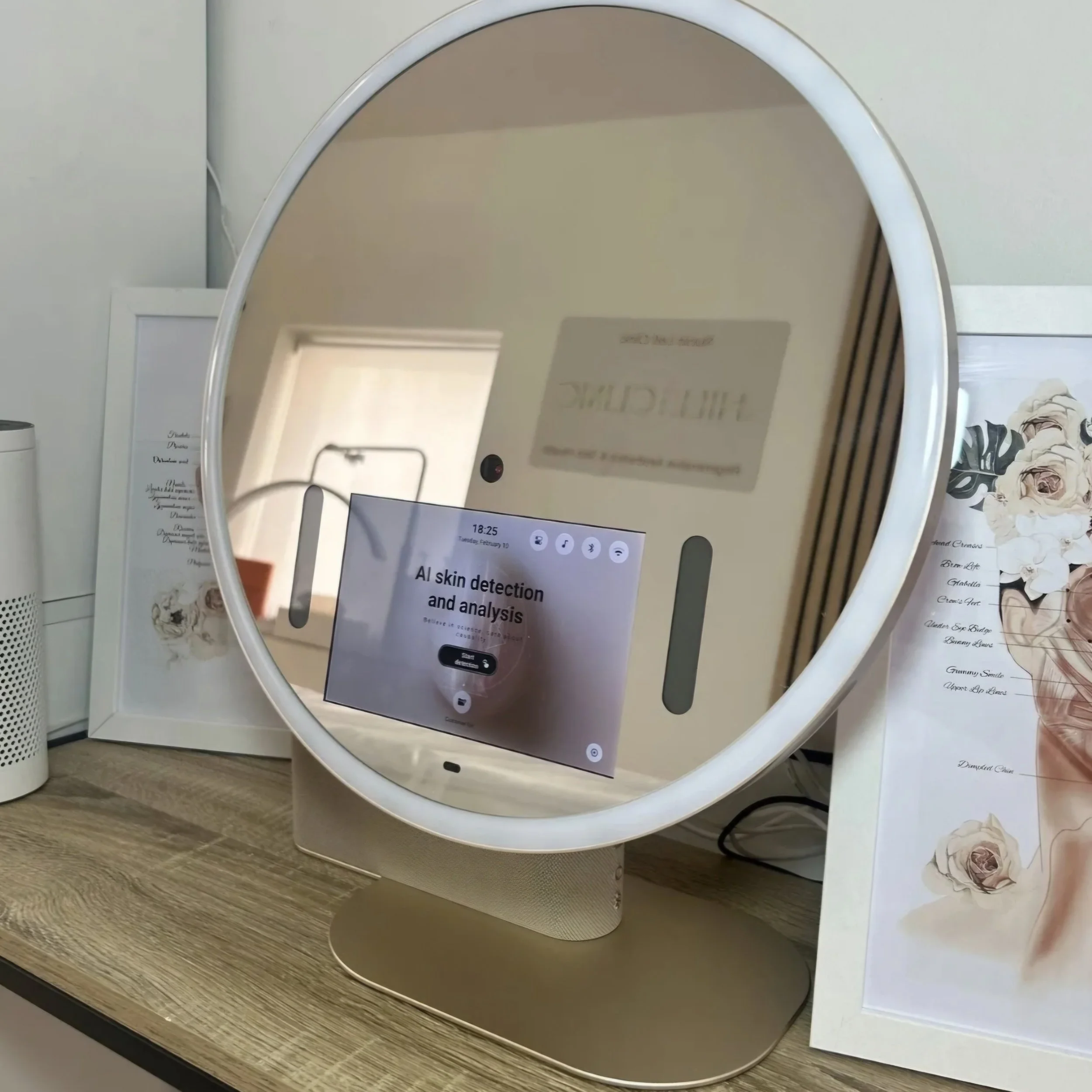 A close-up view of a white device with a circular mirror and a smartphone screen displaying 'AI skin detection and analysis' on a wooden surface, with decorative floral photographs and handwritten notes in the background.
