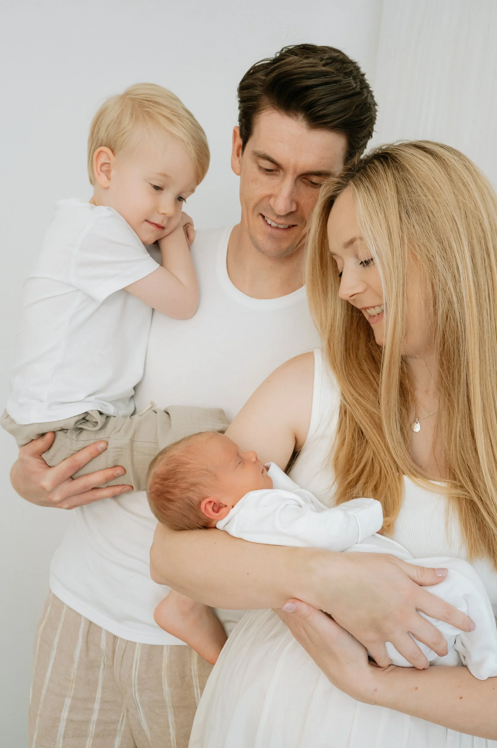 Natural family portrait of parents with their newborn baby and toddler during a relaxed newborn photography session in a natural light studio in Doncaster.