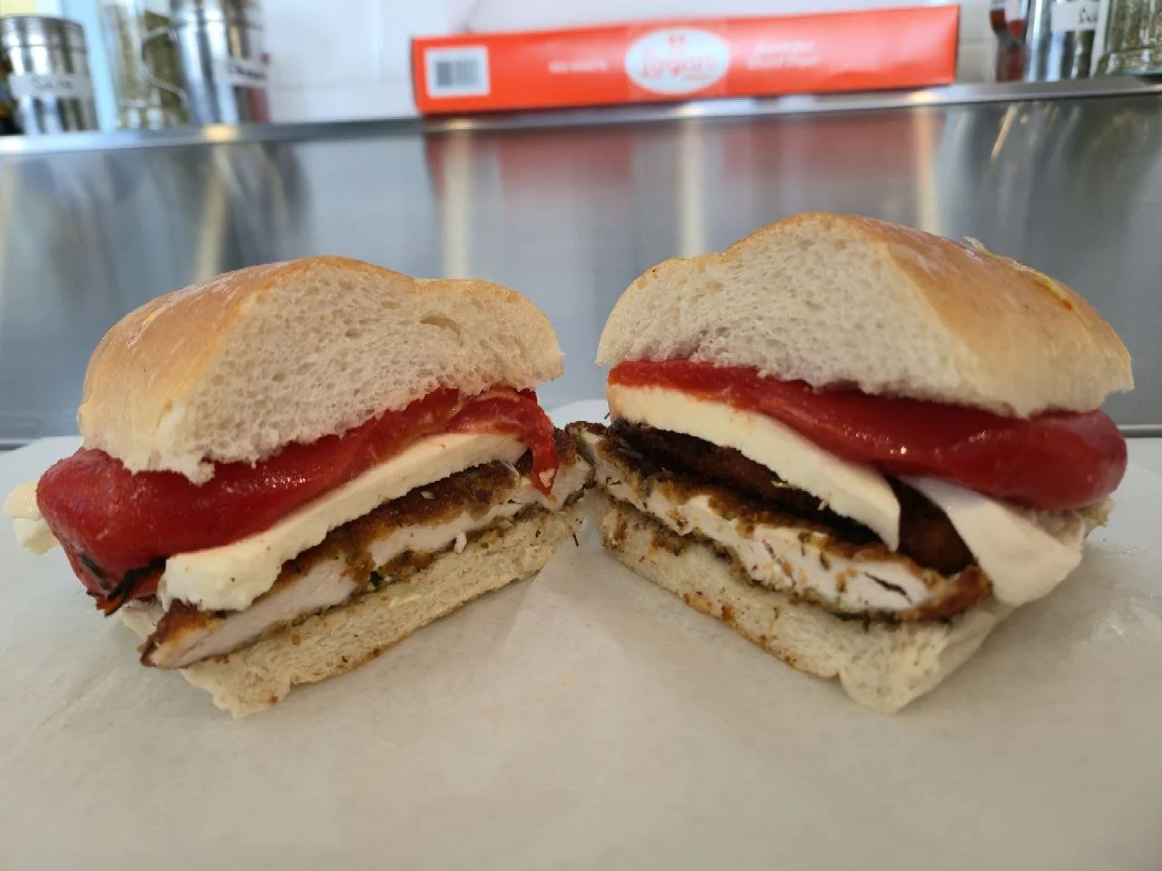 A cut sandwich with turkey, cheese, tomato, and a bun on a white surface.