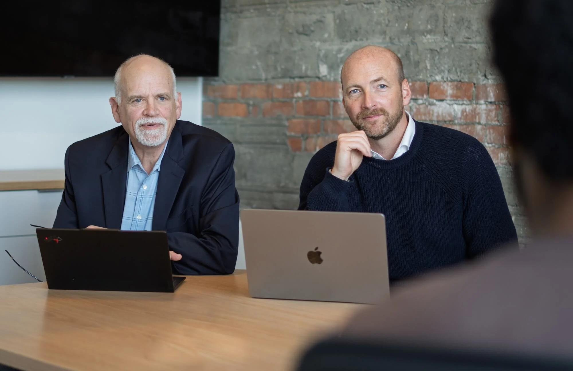 Two men sit in a client meeting at Truscott Rossman.