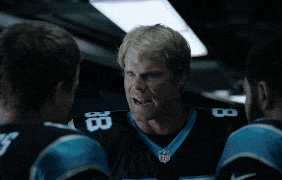 A football coach passionately speaking to players in a locker room.