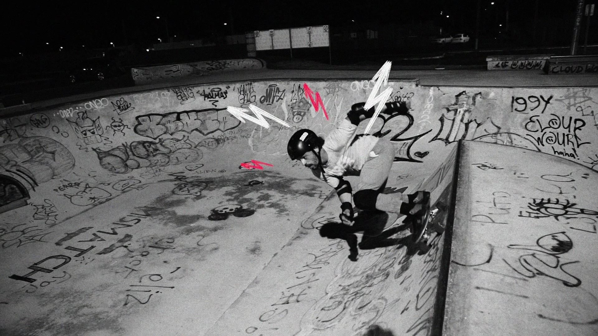 A man skateboarding in a graffiti-covered skate park at night, wearing a helmet and gloves, with pink and white lightning bolt graphics around him.