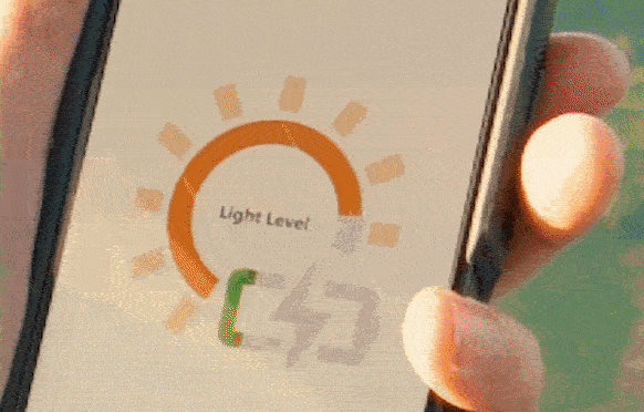 Close-up of a smartphone screen displaying a light level meter with a green indicator pointing to a low light level, held by a person's hand.