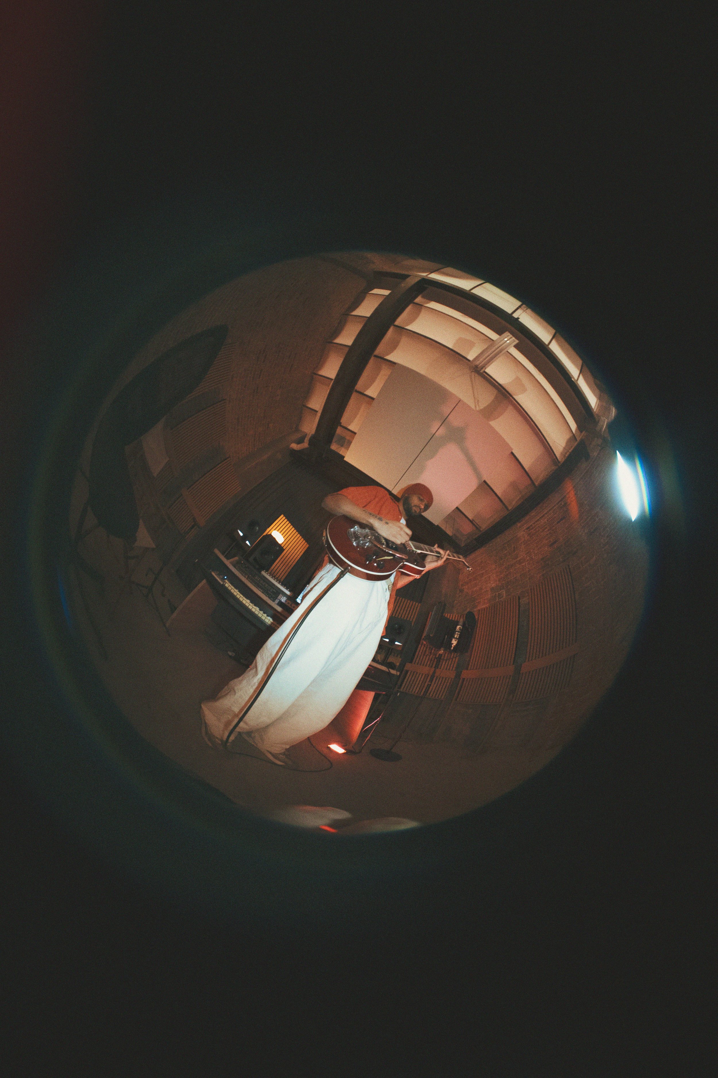 A person playing an acoustic guitar in a recording studio.