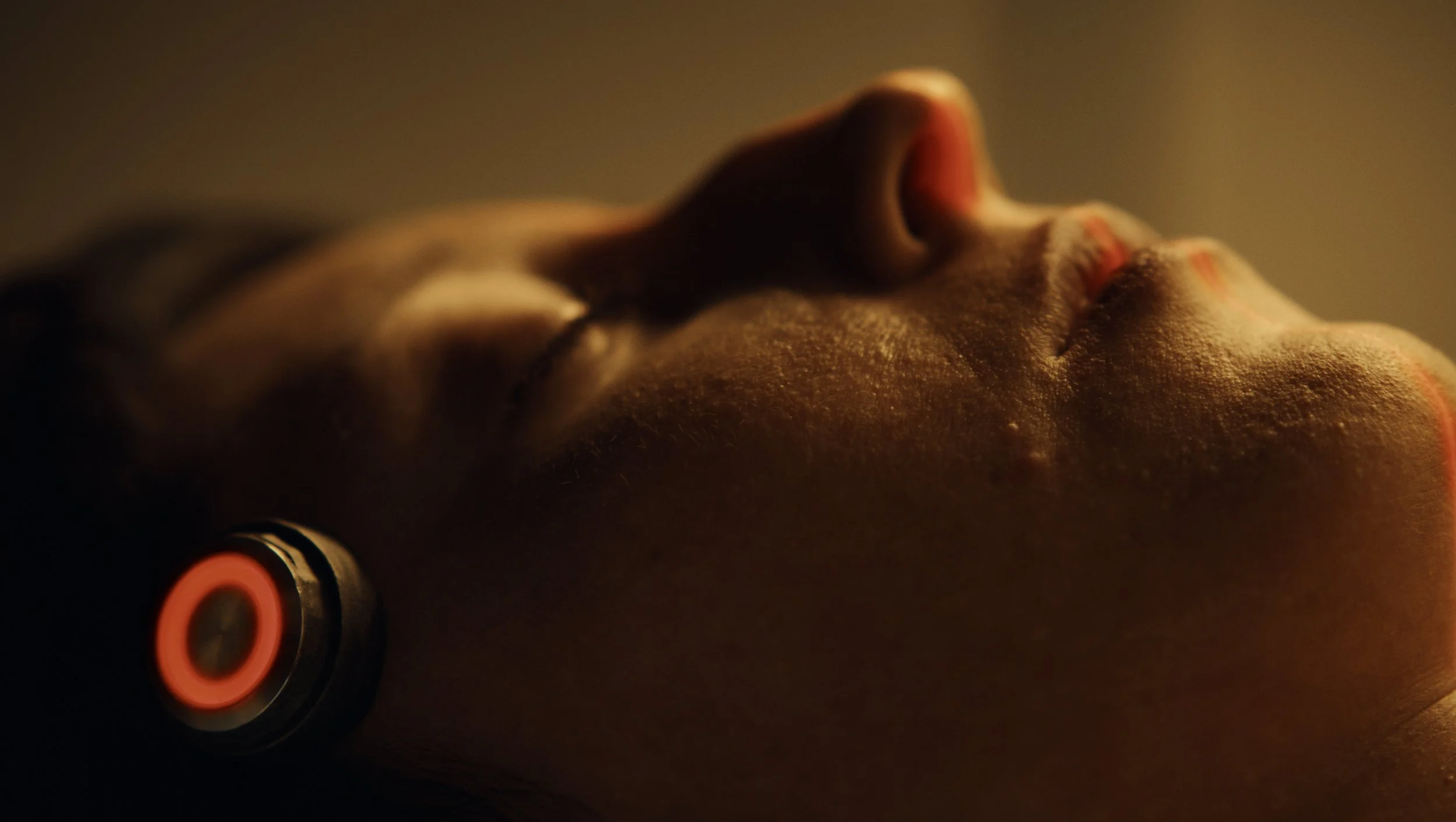 Close-up photo of a person's face lying down with closed eyes, with warm and soft lighting.