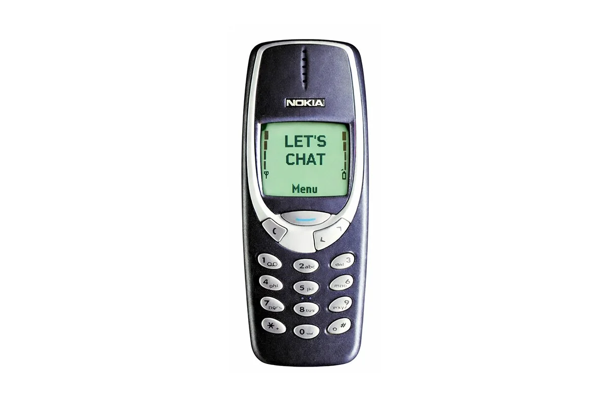 A classic Nokia mobile phone displaying the message "LET'S CHAT" on its screen.