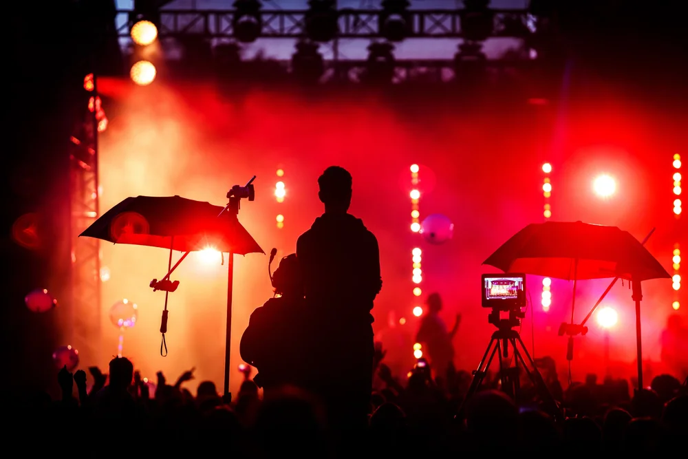 Concert audience facing a brightly lit live music stage