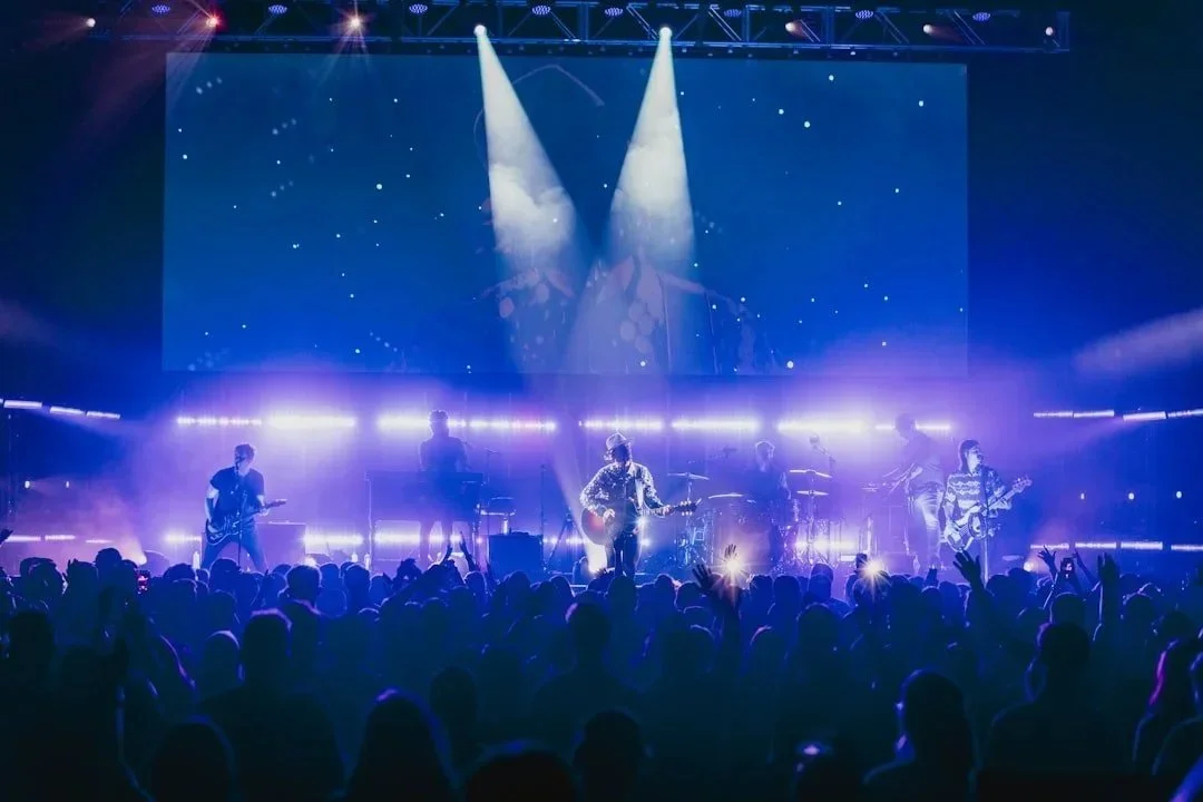 Band performing under purple stage lights in front of a concert crowd