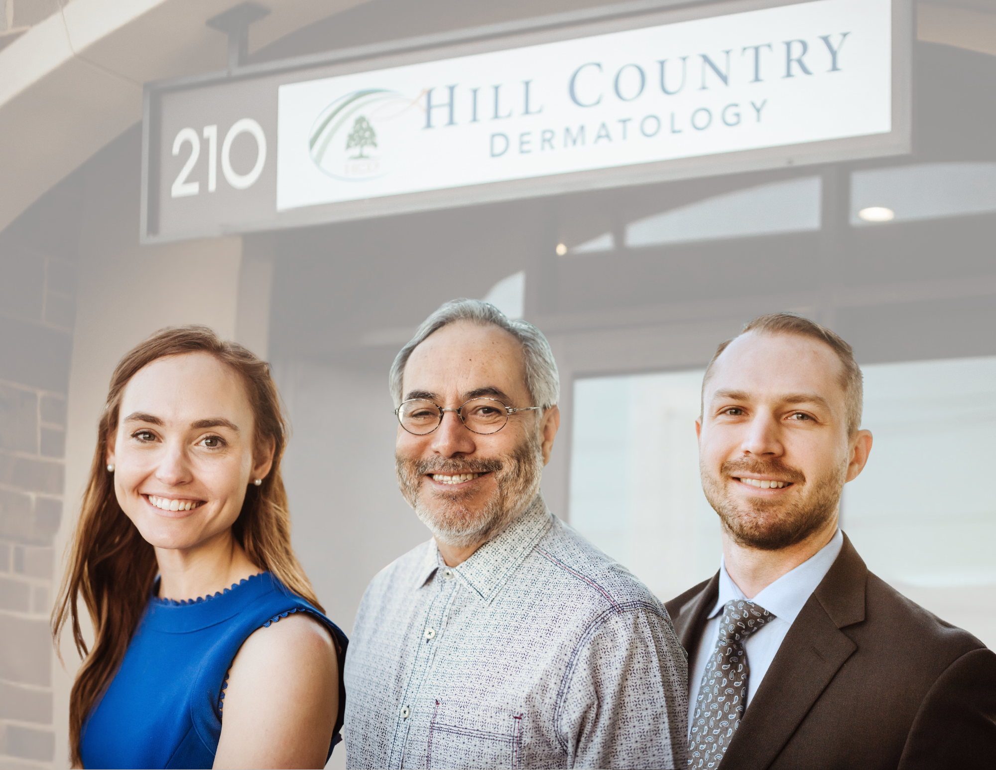Three professionally dressed people standing outside of Hill Country Dermatology clinic, smiling at the camera.