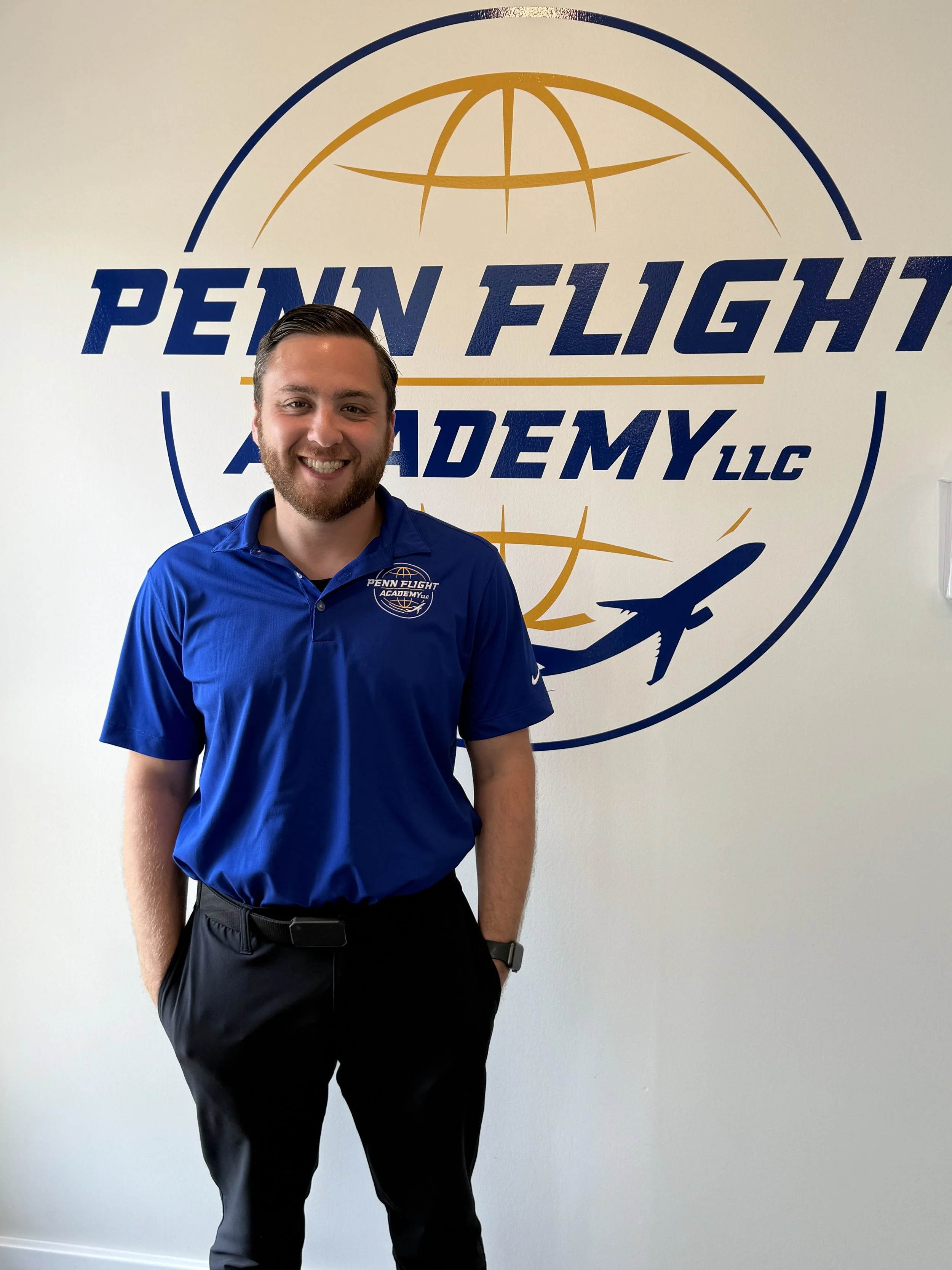 Person in sunglasses wearing a Penn Flight School polo shirt, standing next to an aircraft propeller.